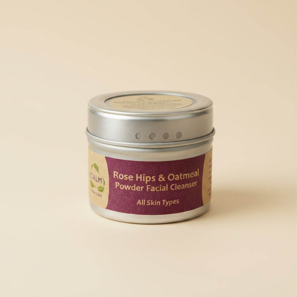 A cylindrical container of CALM Rose Hips & Oatmeal Powder Facial Cleanser with a label that includes the product name and the statement 'All Skin Types'. The container is metallic with a textured lid and a branding label on the front.